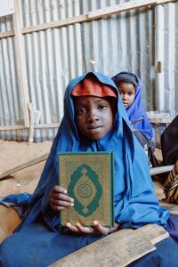 free photo of child holding quran in traditional setting