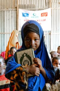 free photo of young girl holding quran in community gathering
